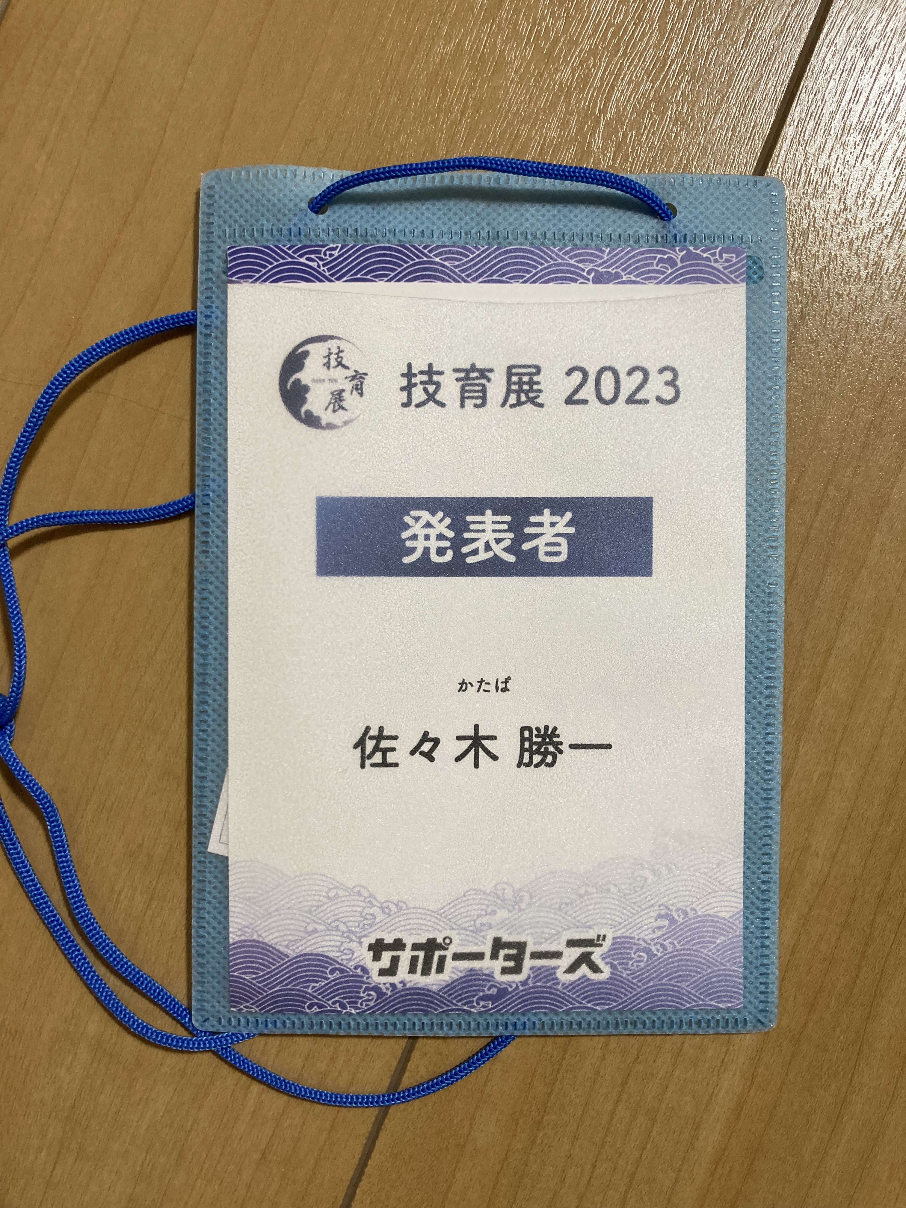 名札．上から順に，技育展2023・発表者・かたぱ・佐々木勝一・サポーターズ，という文字列が記述されている．